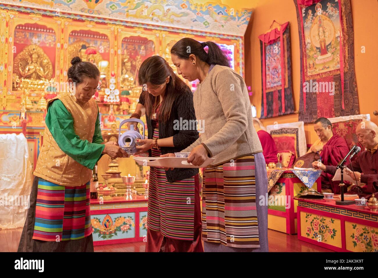 3 devout Buddhist worshippers prepare hot tea for the monks and congregants prior to a Tsu Che Puja at a temple in Elmhurst, Queens, New York City. Stock Photo