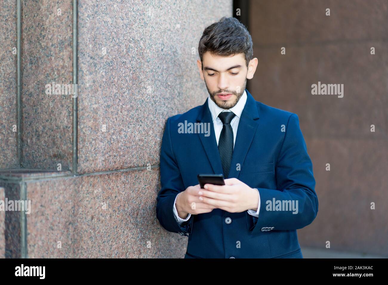 Hipster businessman with beard and suit and mobile phone outdoor in summer in city Stock Photo