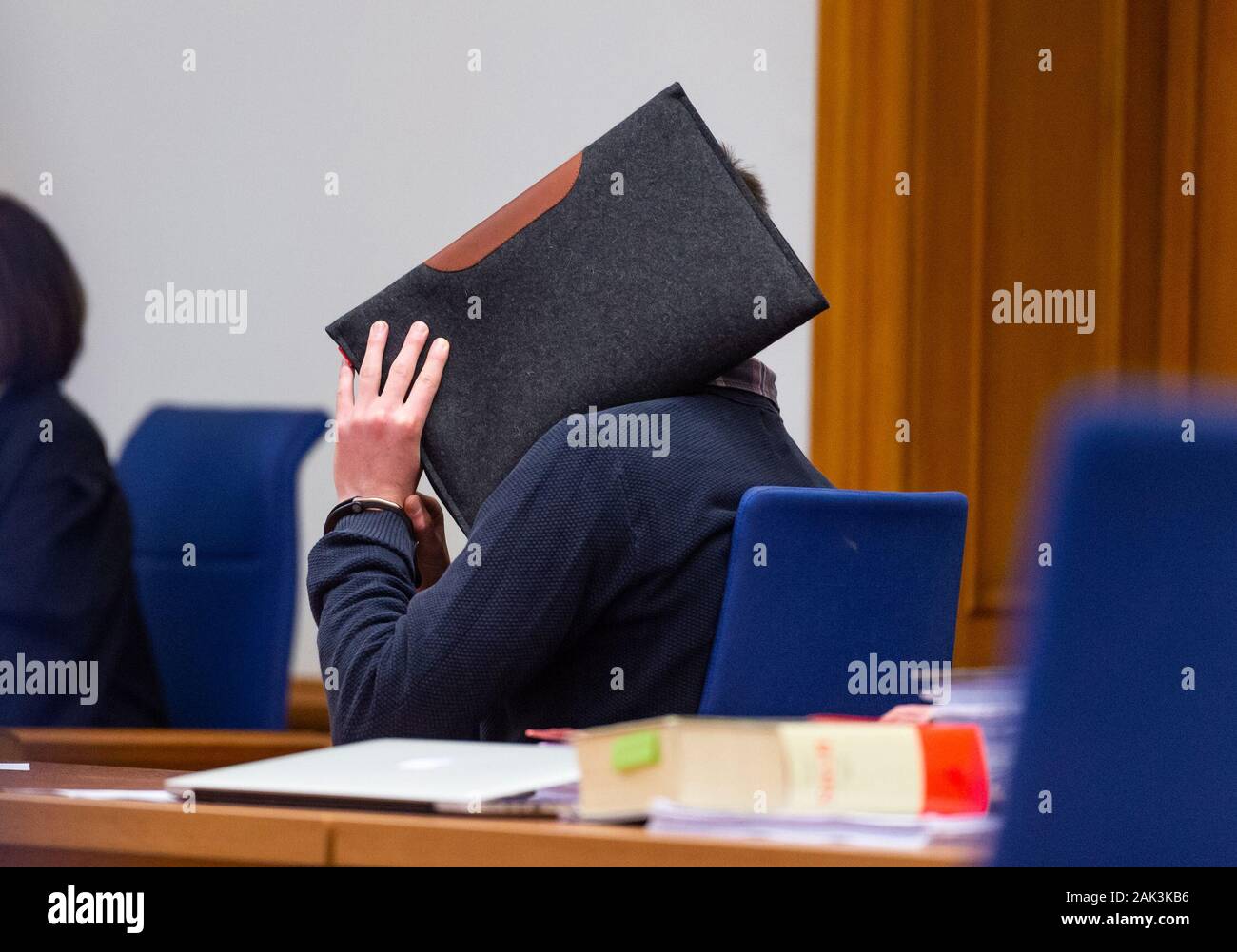 07 January 2020, Lower Saxony, Lüneburg: Before the trial begins, the accused sits in the Lüneburg Regional Court with a steward in front of his face. The 26-year-old is alleged to have sexually abused several children in Lueneburg and other places as trainer and supervisor of a DLRG local group. Photo: Philipp Schulze/dpa Stock Photo