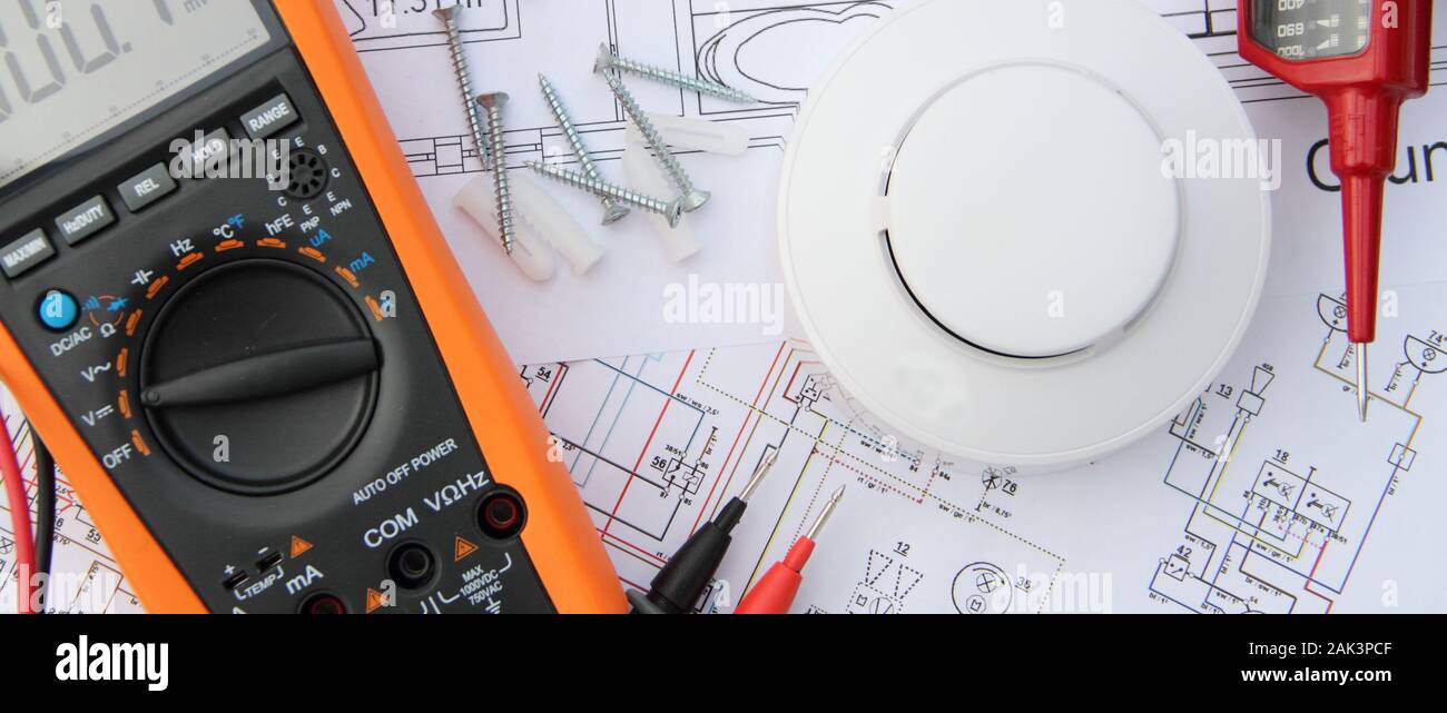 smoke detector with a screwdriver and a measuring device on a circuit diagram Stock Photo