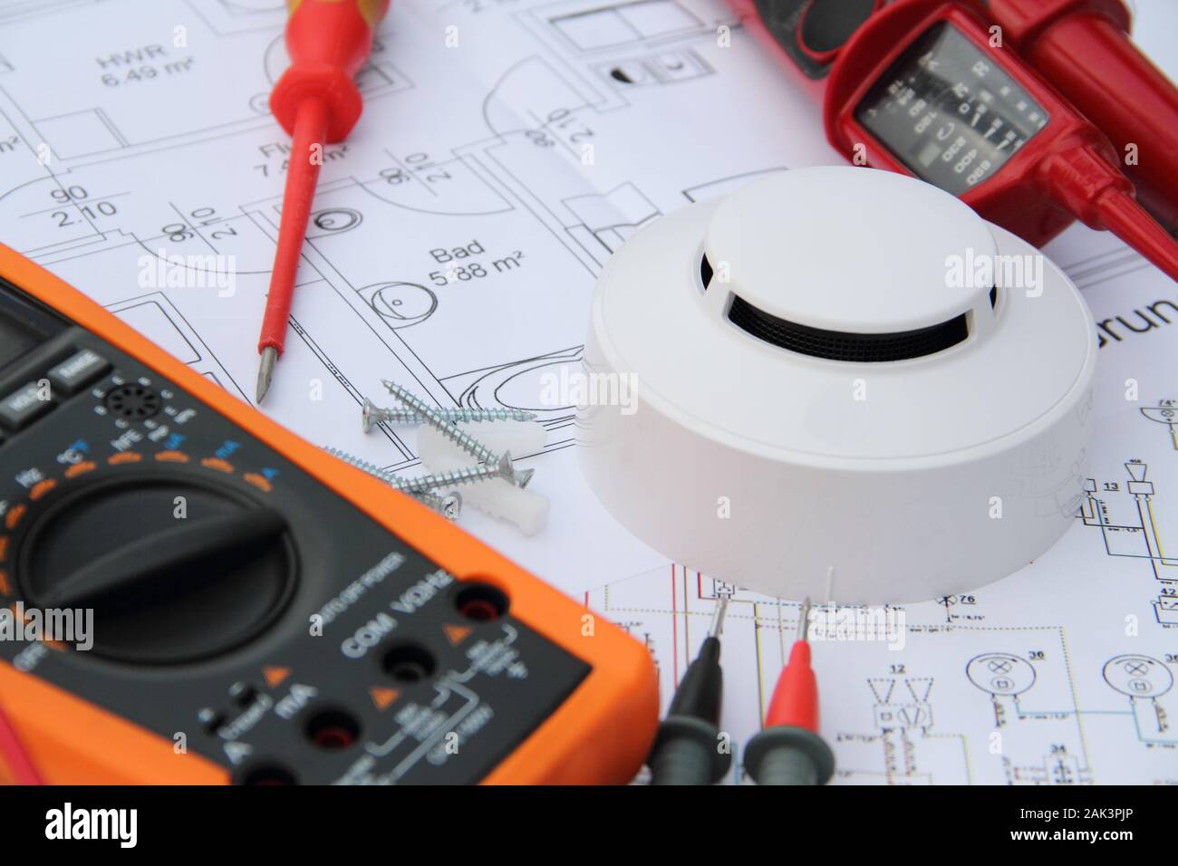 smoke detector with a screwdriver and a measuring device on a circuit diagram Stock Photo