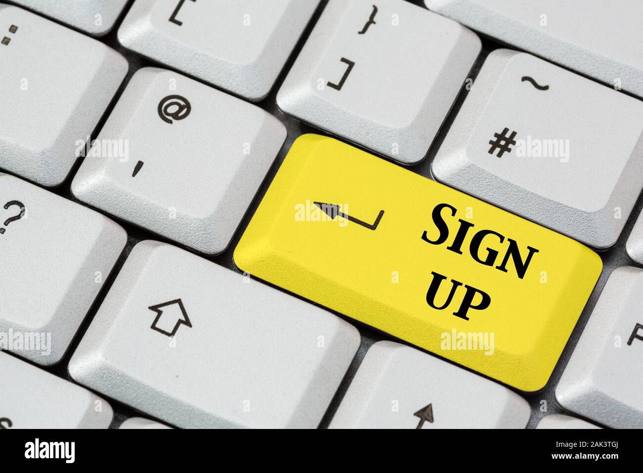 A keyboard with Sign up written in black lettering on a yellow enter key to illustrate joining concept. England, UK, Britain Stock Photo