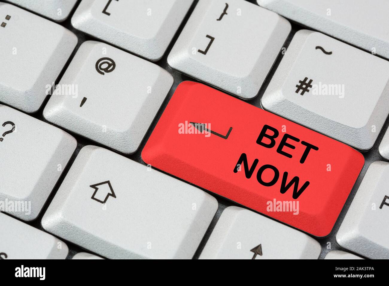 A keyboard with Bet Now written in black lettering on a red enter key. Online betting internet gambling payment concept. England, UK, Britain Stock Photo