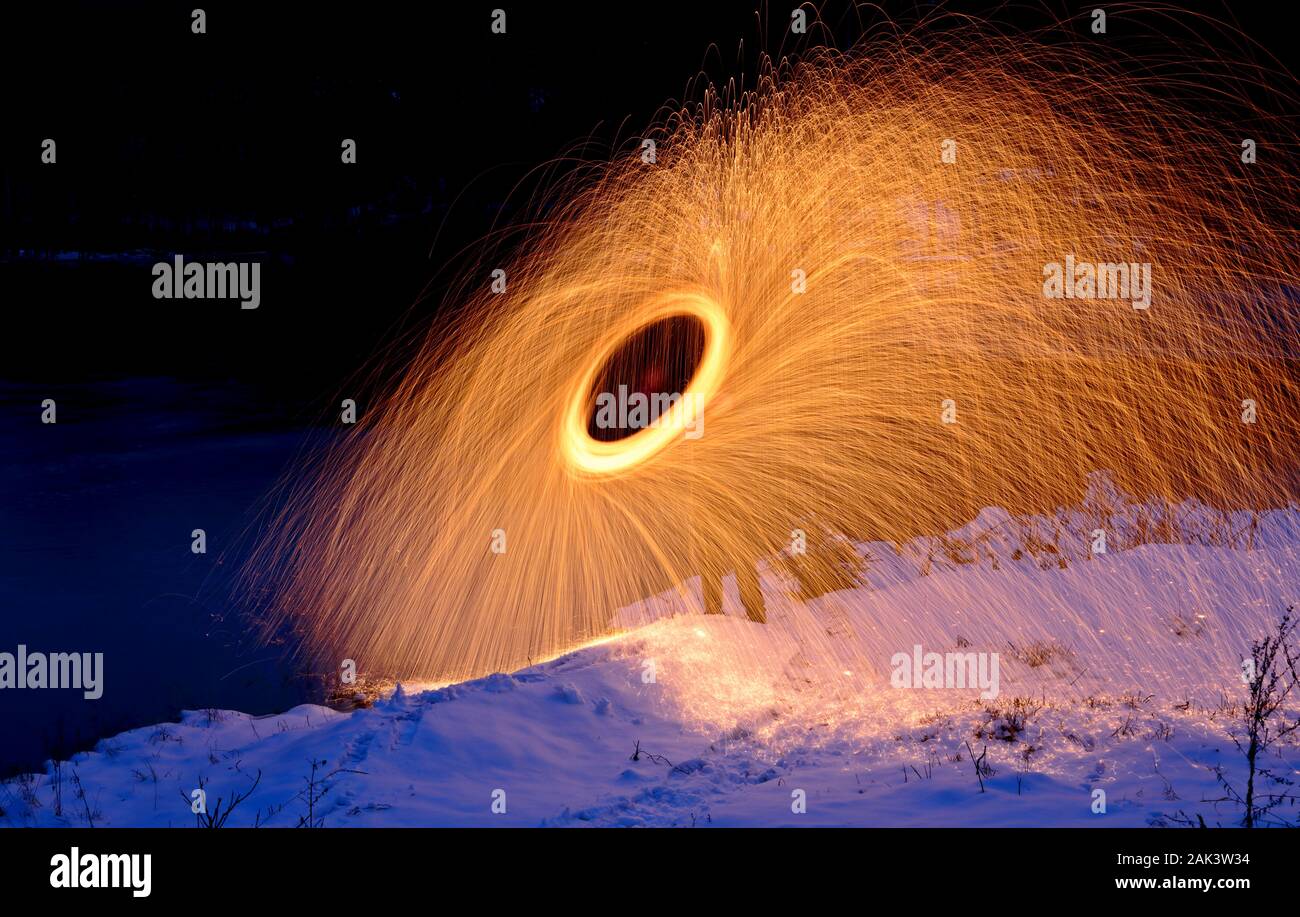 Burning steel wool fireworks spinning next to a lake Stock Photo