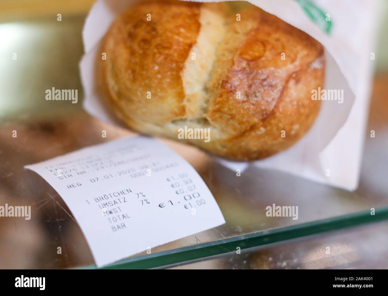 07 January 2020, Saxony, Leipzig: A bread roll and the corresponding receipt are lying on the counter of a pastry shop. Just a few days after the controversial obligation to pay receipts came into force, the regulation has met with criticism, especially from bakeries. Customers would not take the vouchers with them and the bakeries would have to throw away the freshly printed voucher right away, according to representatives of the bakers' guild. Since 1 January, merchants have had to hand over a receipt to their customers. The law on cash registers passed in 2016 is intended to combat tax frau Stock Photo
