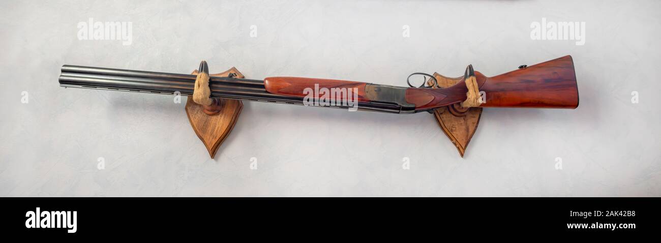 Hunting rifle hanging on a wall with deer foot gun rack Stock Photo