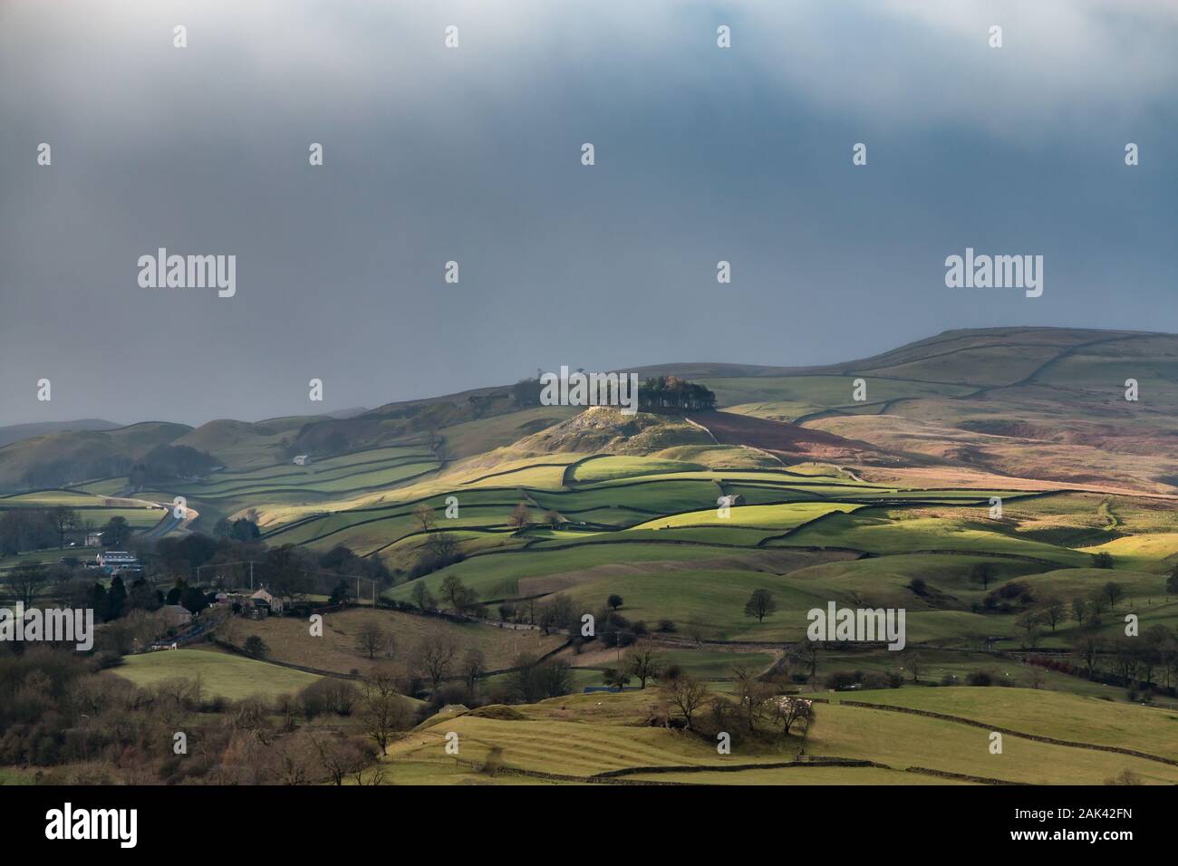 A break in the clouds creates very strong winter sunshine and lights up Kirkcarrion, Teesdale's iconic landmark, on an otherwise dull day in January Stock Photo