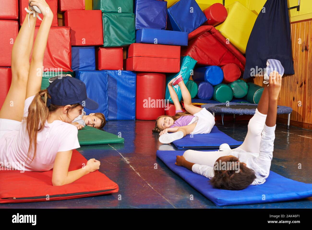 Children do gymnastics in kindergarten together with the teacher in the gym Stock Photo