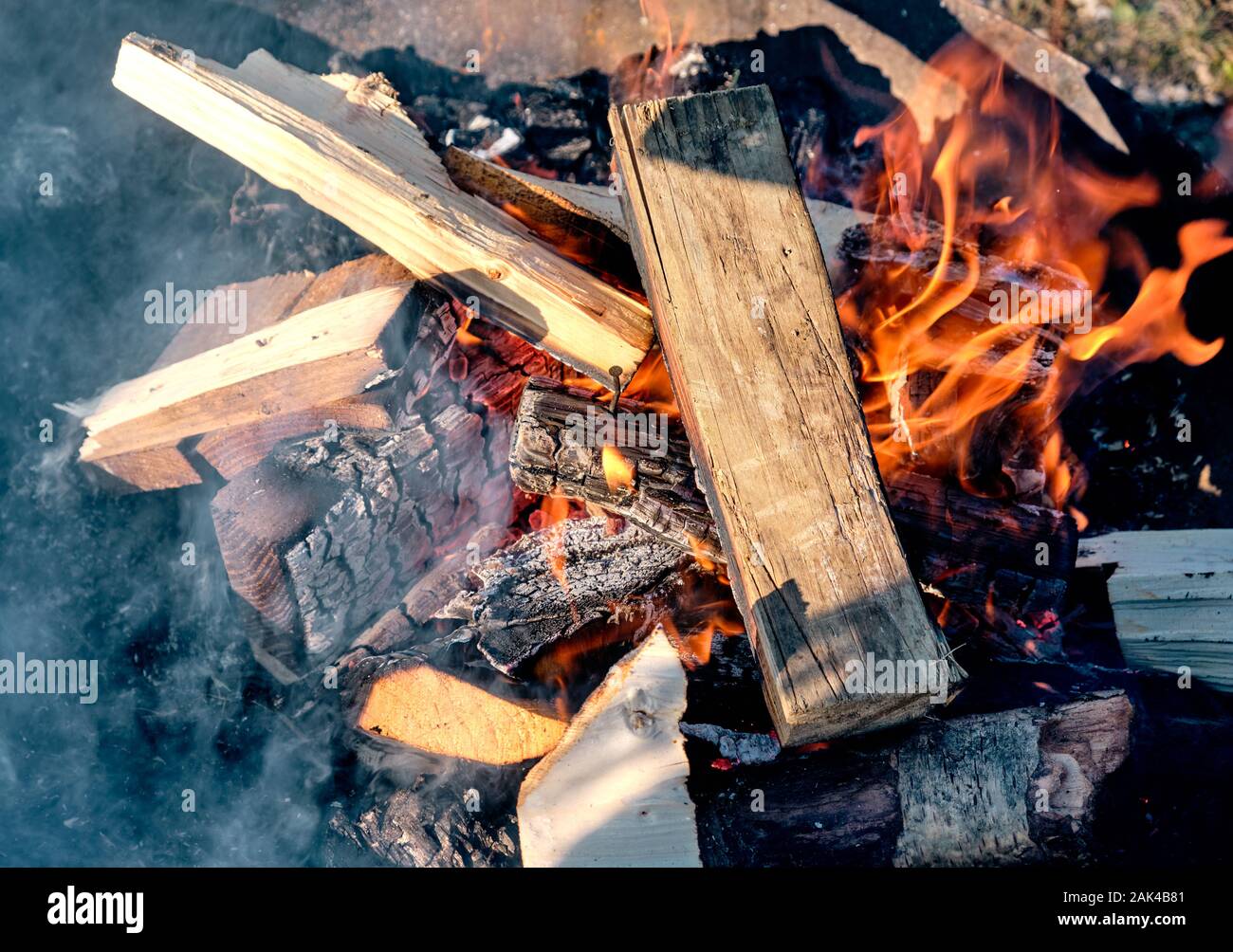 Bonfire with orange flames, new logs and a beautiful hot glow burning outdoors in a firebowl made of steel. Seen in Bavaria, Germany in January Stock Photo