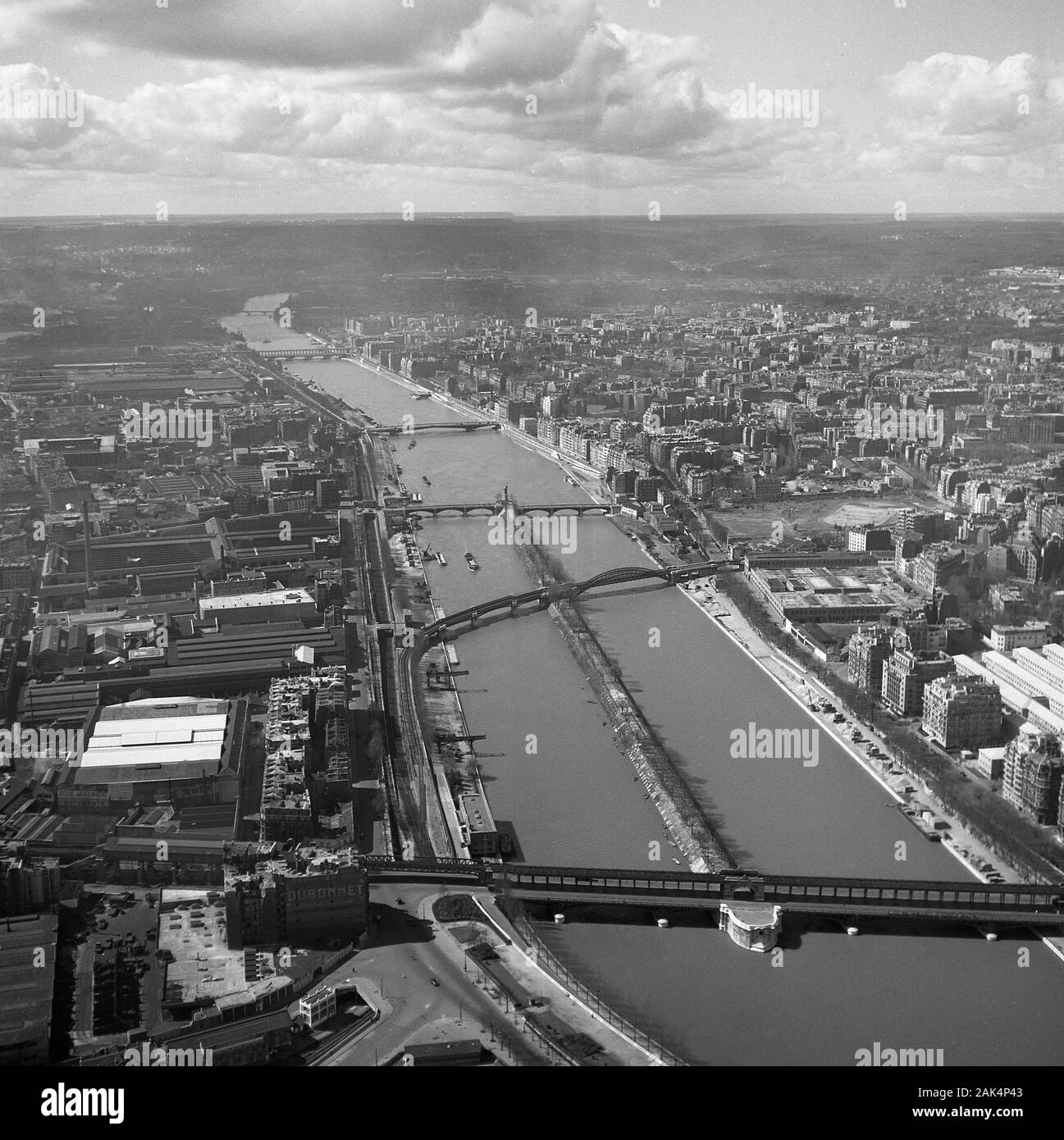 1950s, historical, aerial view from the Eiffel Tower over the river Seine and the city of Paris, France, showing the bridges of the day, including the little 'Statue of Liberty' positioned on the ile aux Cygnes (Isle of the Swans) in the middle of the river. Stock Photo