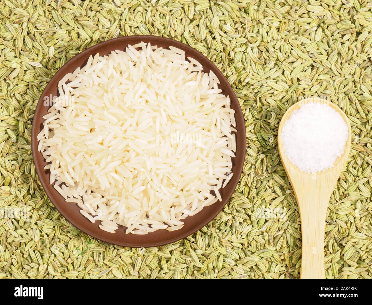 Rice in clay plate, salt. Background from Fennel. Indian cuisine