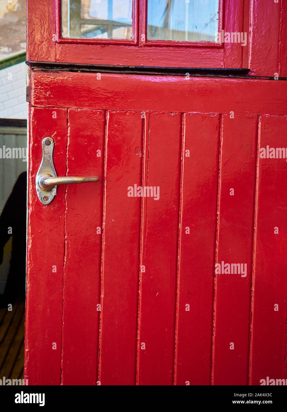 Antique red wooden door with a metallic door handle. Stock Photo