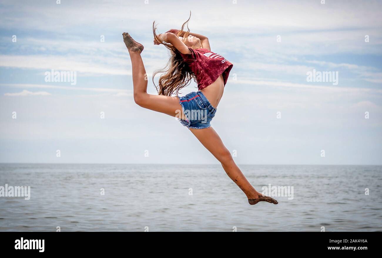 Beautiful teenage girl dancing and jumping on the beach Stock Photo