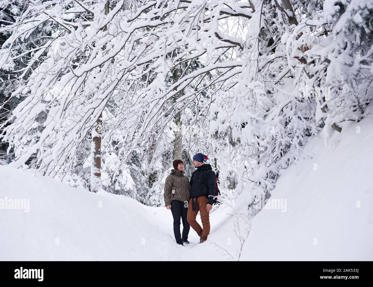 Smiling couple standing in a snowy forest while out hiking Stock Photo