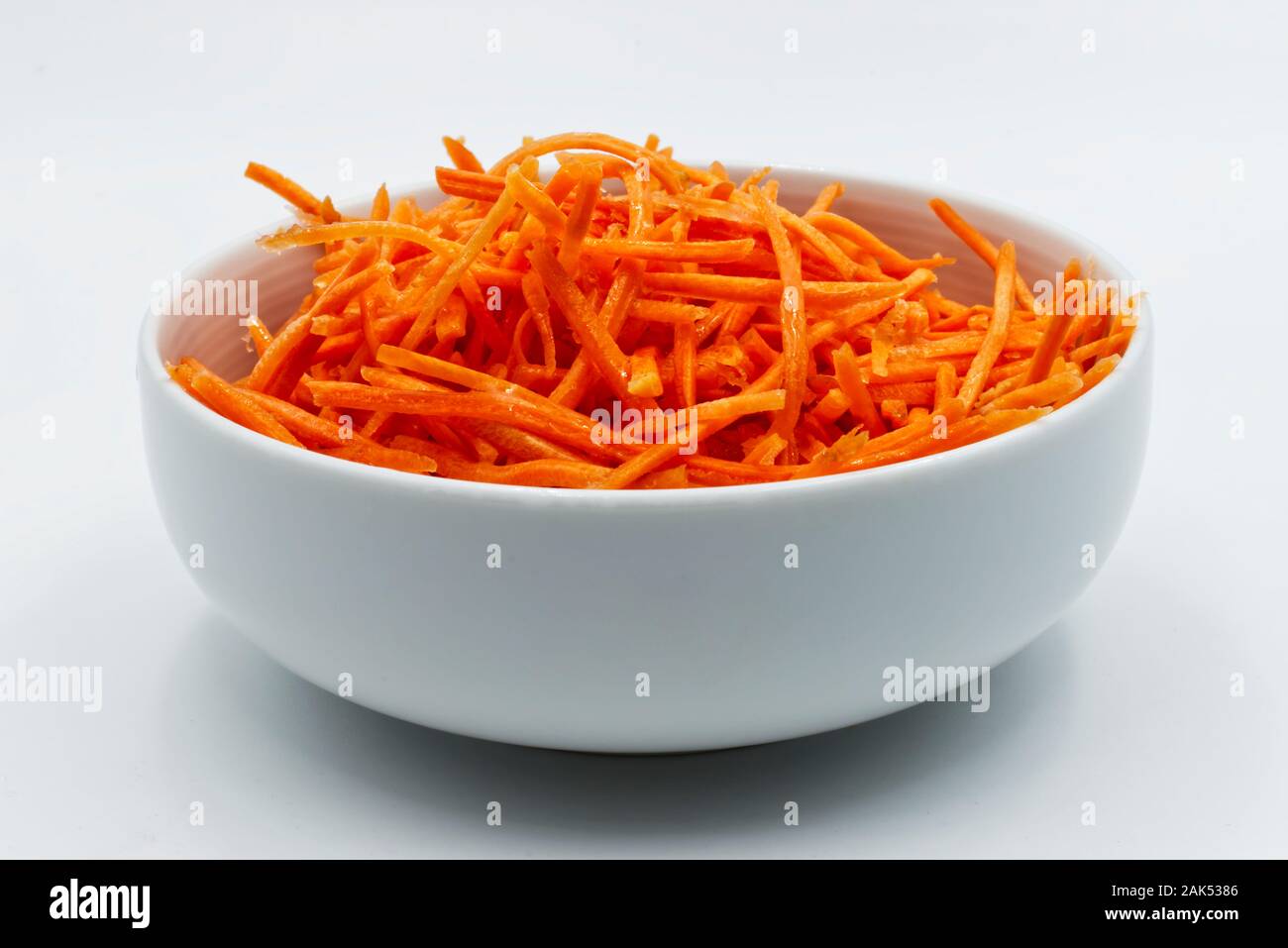 Carrots sliced in a white bowl, isolated on white background Stock Photo