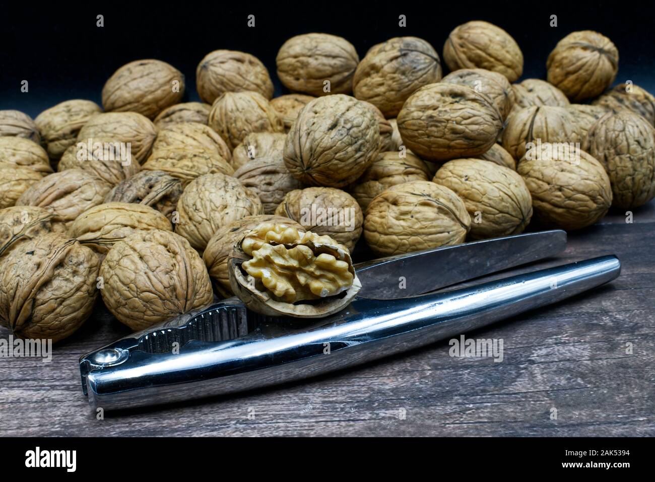Walnuts with metal nutcracker on a wooden background Stock Photo
