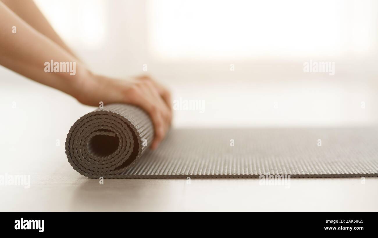 Pilates Concept Woman Rolling Up Yoga Mat After Training Side