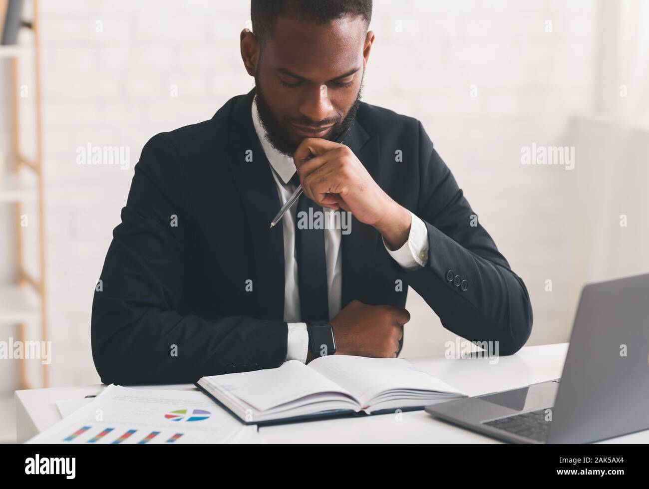 Close up portrait of pensive afro man economist working with papers in office Stock Photo