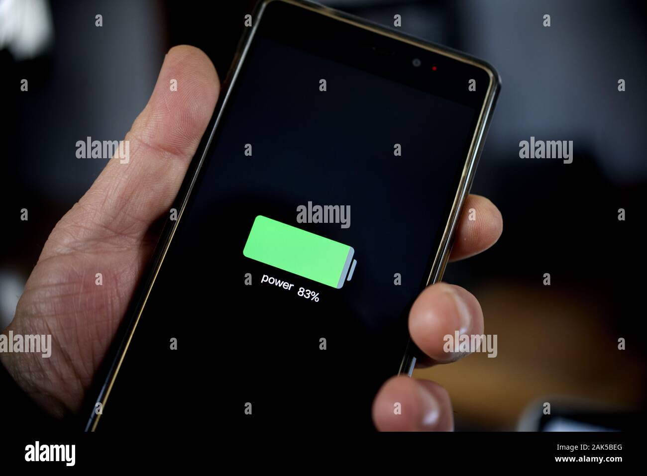 hand holding smartphone showing battery level after charge Stock Photo