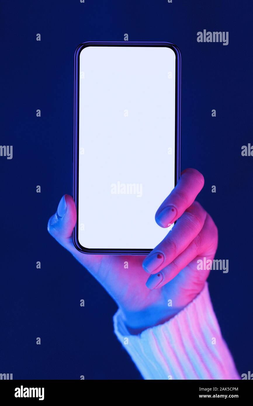 Female hand demonstrating modern smartphone with blank screen in neon ...
