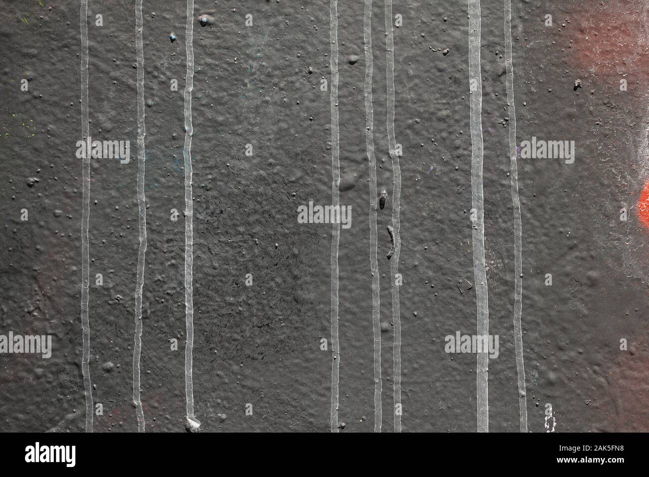 Textured black wall with dripping white paint. Abstract background