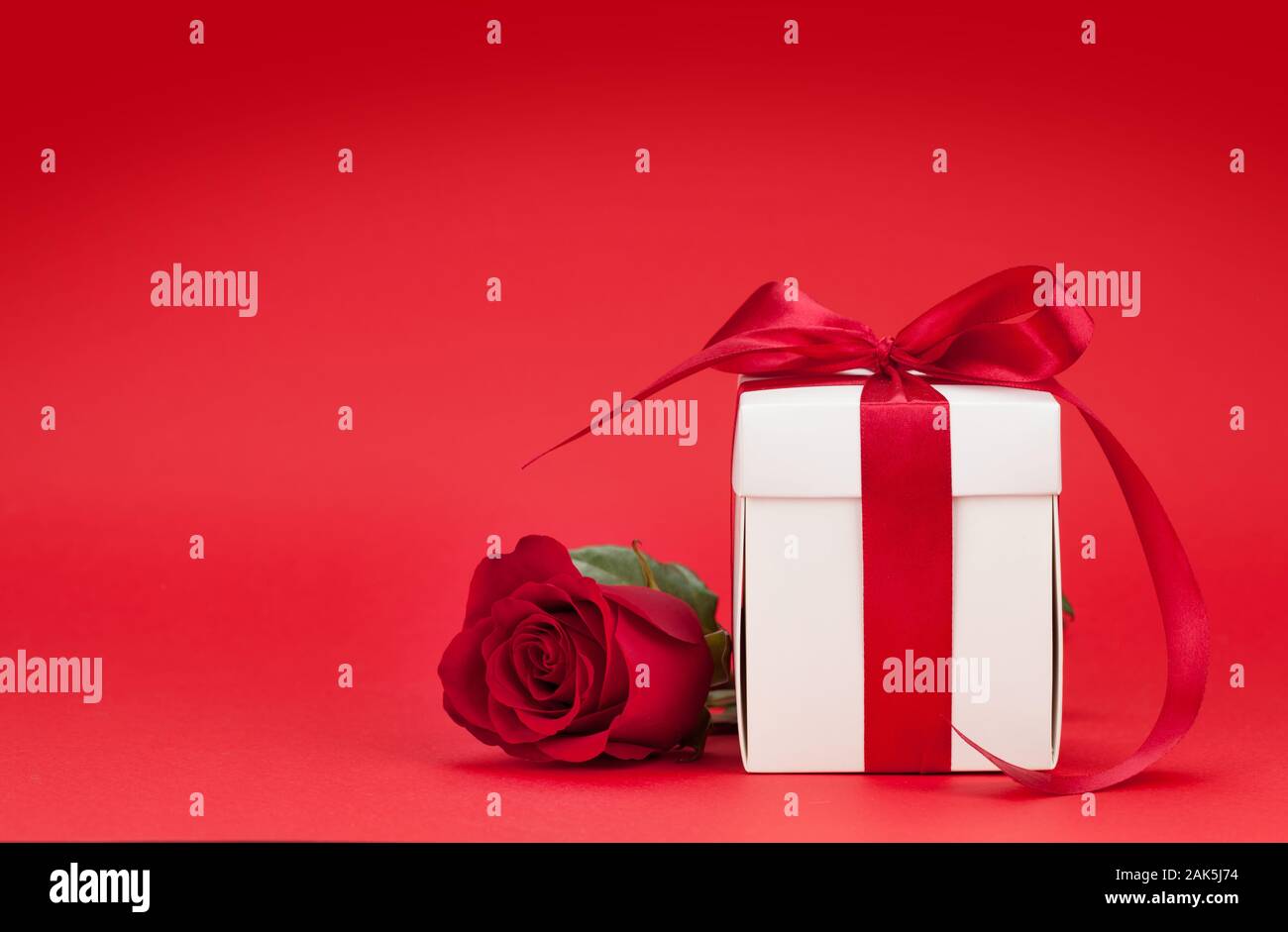 Valentines day greeting card with rose flower and gift box over red ...