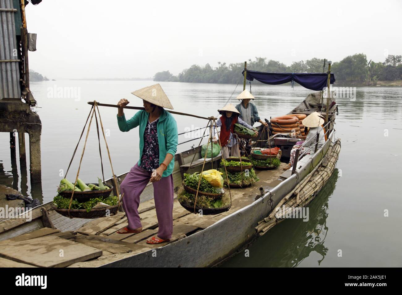 Hue: Frau mit Kegelhut auf dem Weg zum oertlichen Markt in Bao Vinh, Vietnam | usage worldwide Stock Photo