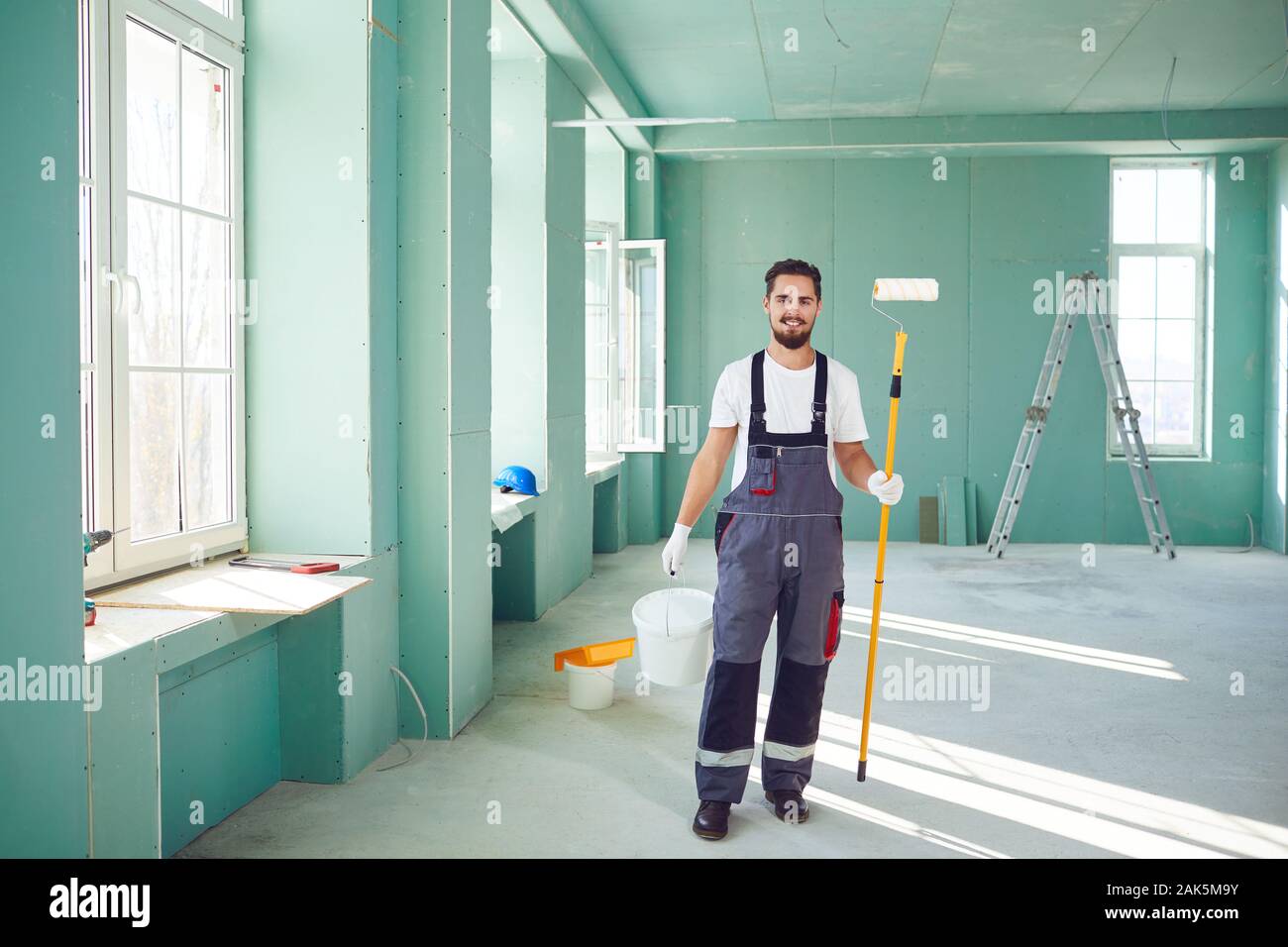 Bearded painter smiling construction worker with tools on a construction site. Stock Photo