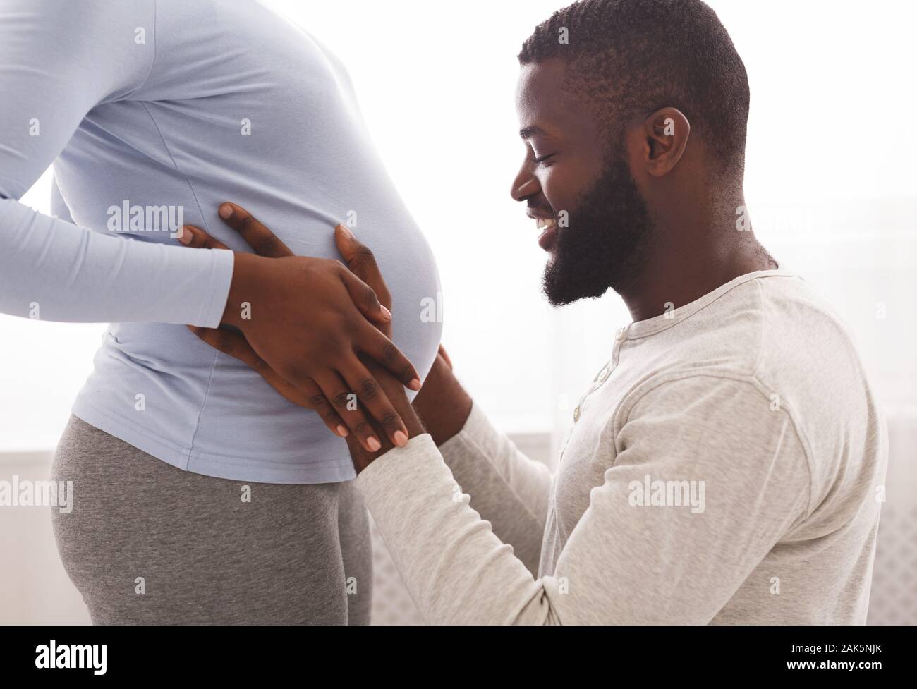 Happy african husband touching his pregnant wife belly at home, close ...