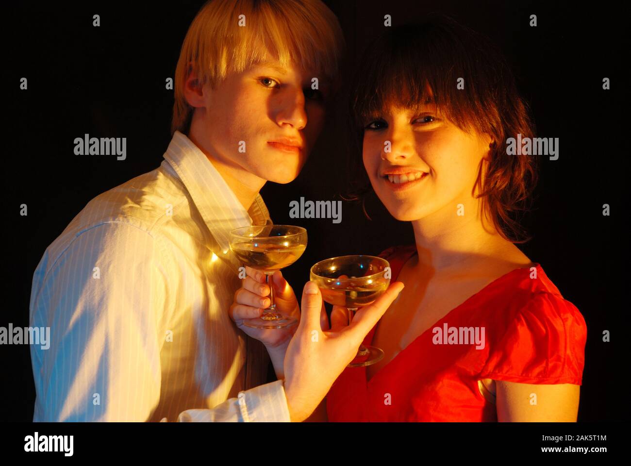 Young couple drinking a toast, looking at the camera. Stock Photo