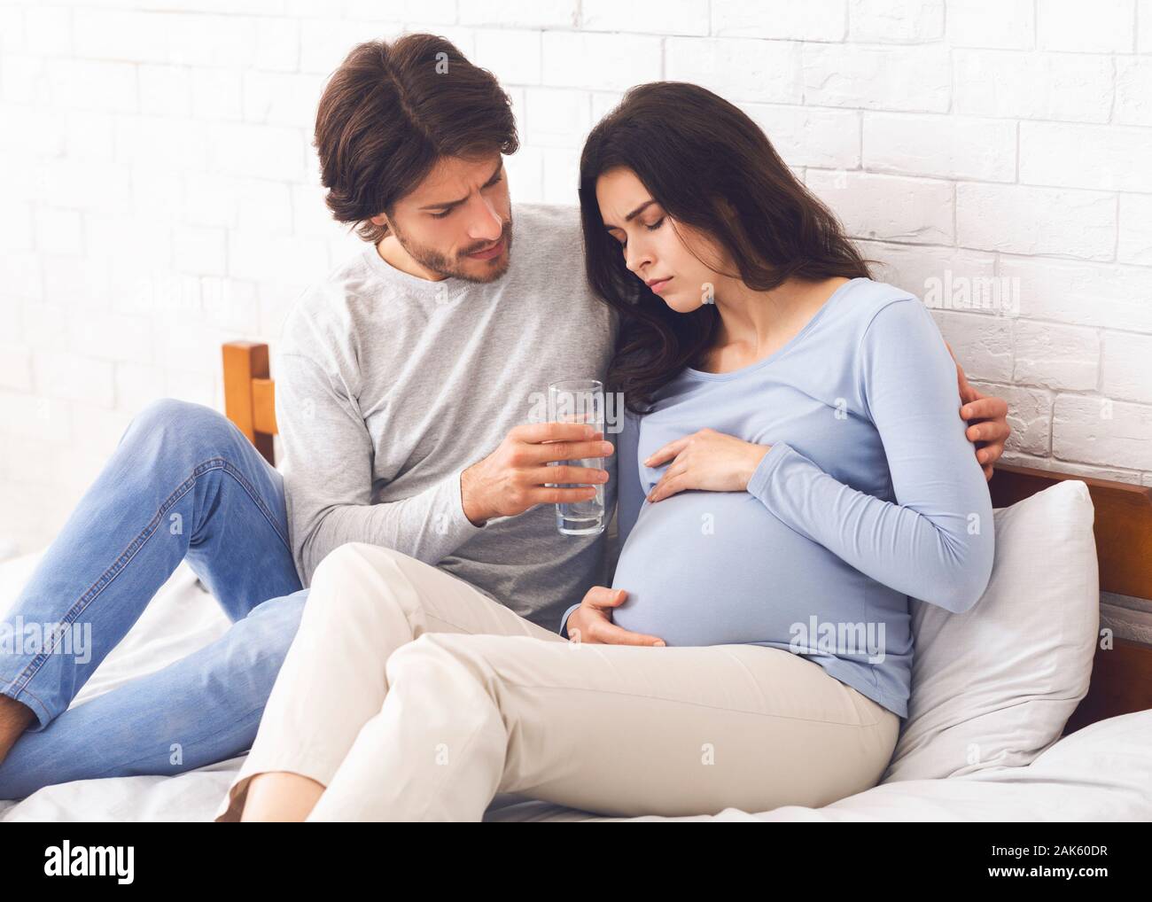 Caring Husband Giving Glass Of Water To His Pregnant Wife That Feeling