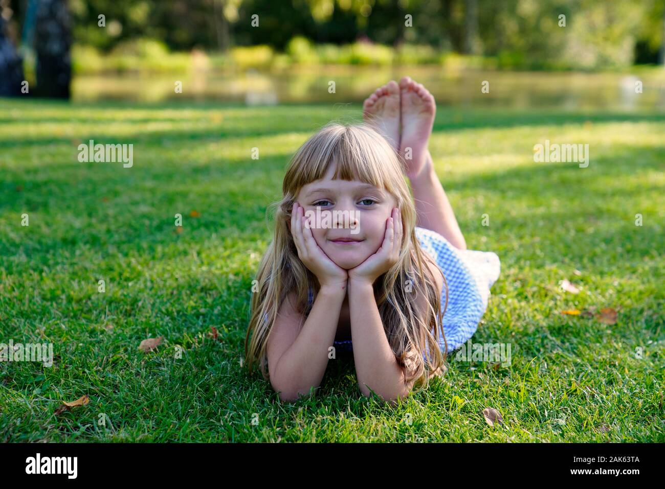 Girl lying on a meadow with her head propped up, 6 years, portrait, Czech Republic Stock Photo