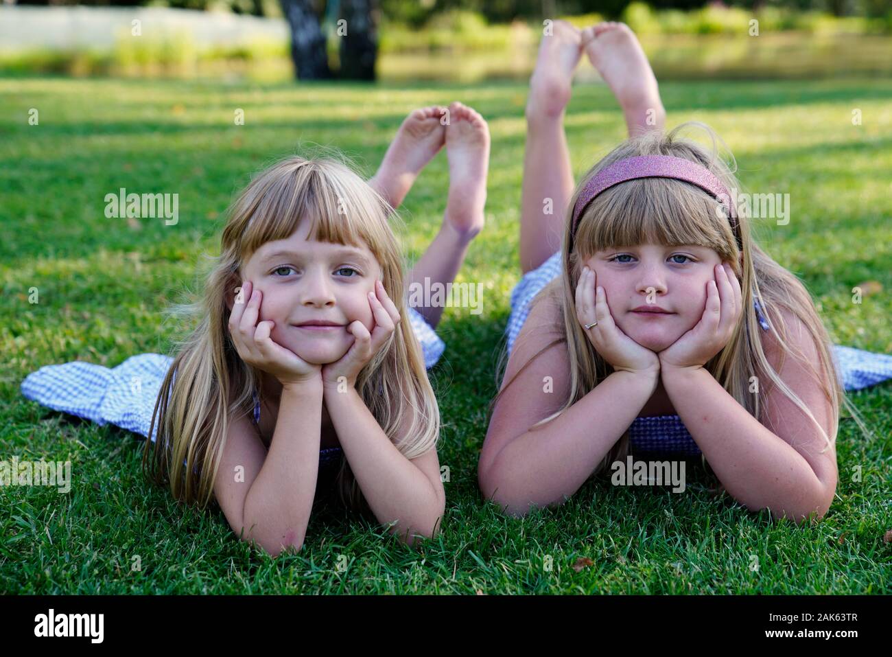 Two girls, siblings lying on the meadow with their heads propped up, 6 and 7 years, portrait, Czech Republic Stock Photo