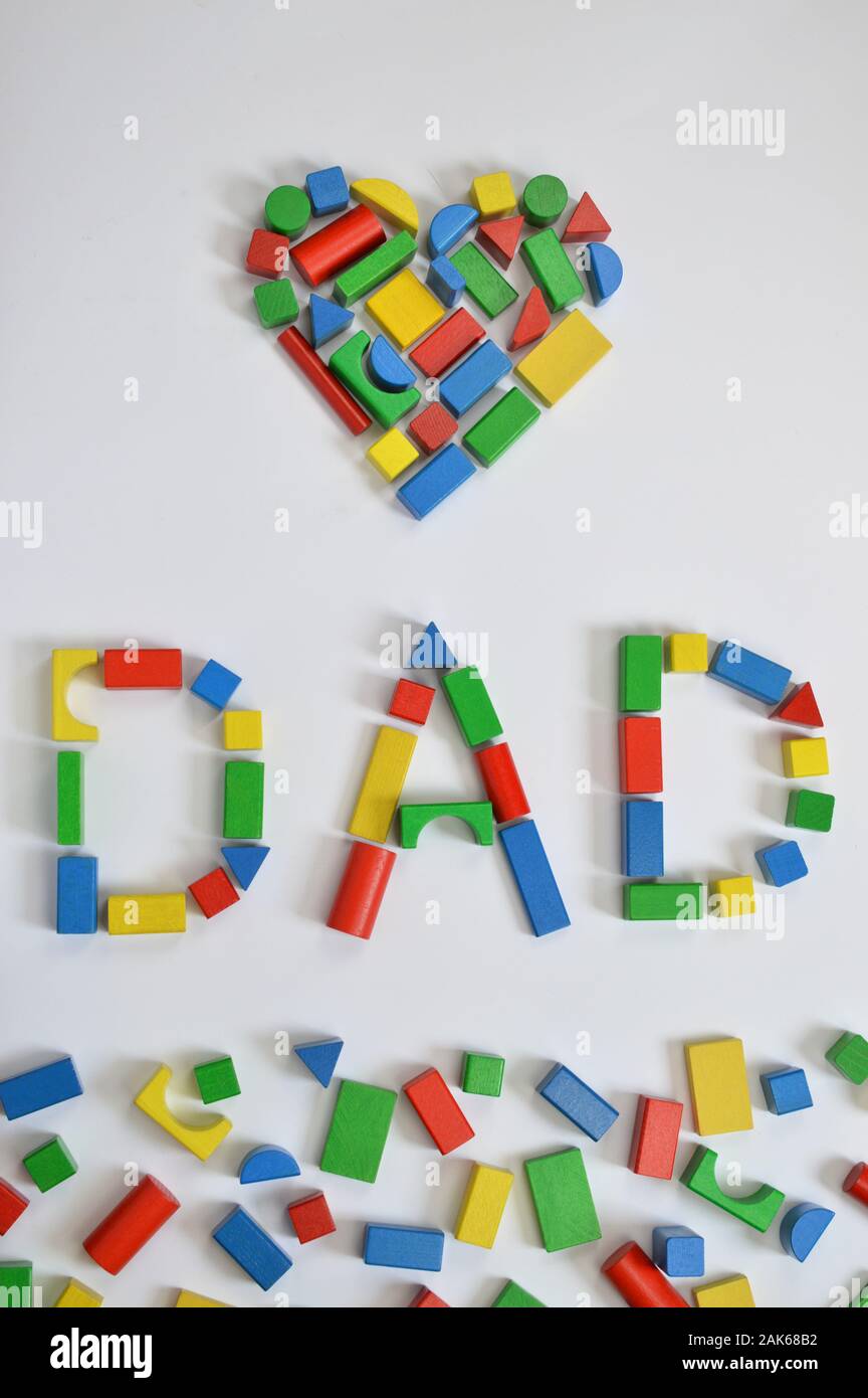 colorful wooden toy blocks lettering the word DAD and a heart on white ...