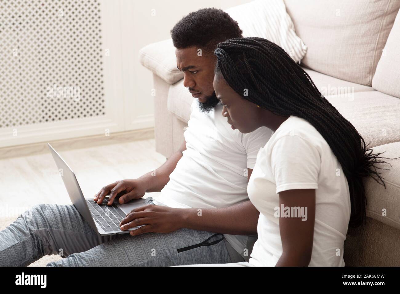 Happy African American couple using laptop together at home, browsing ...