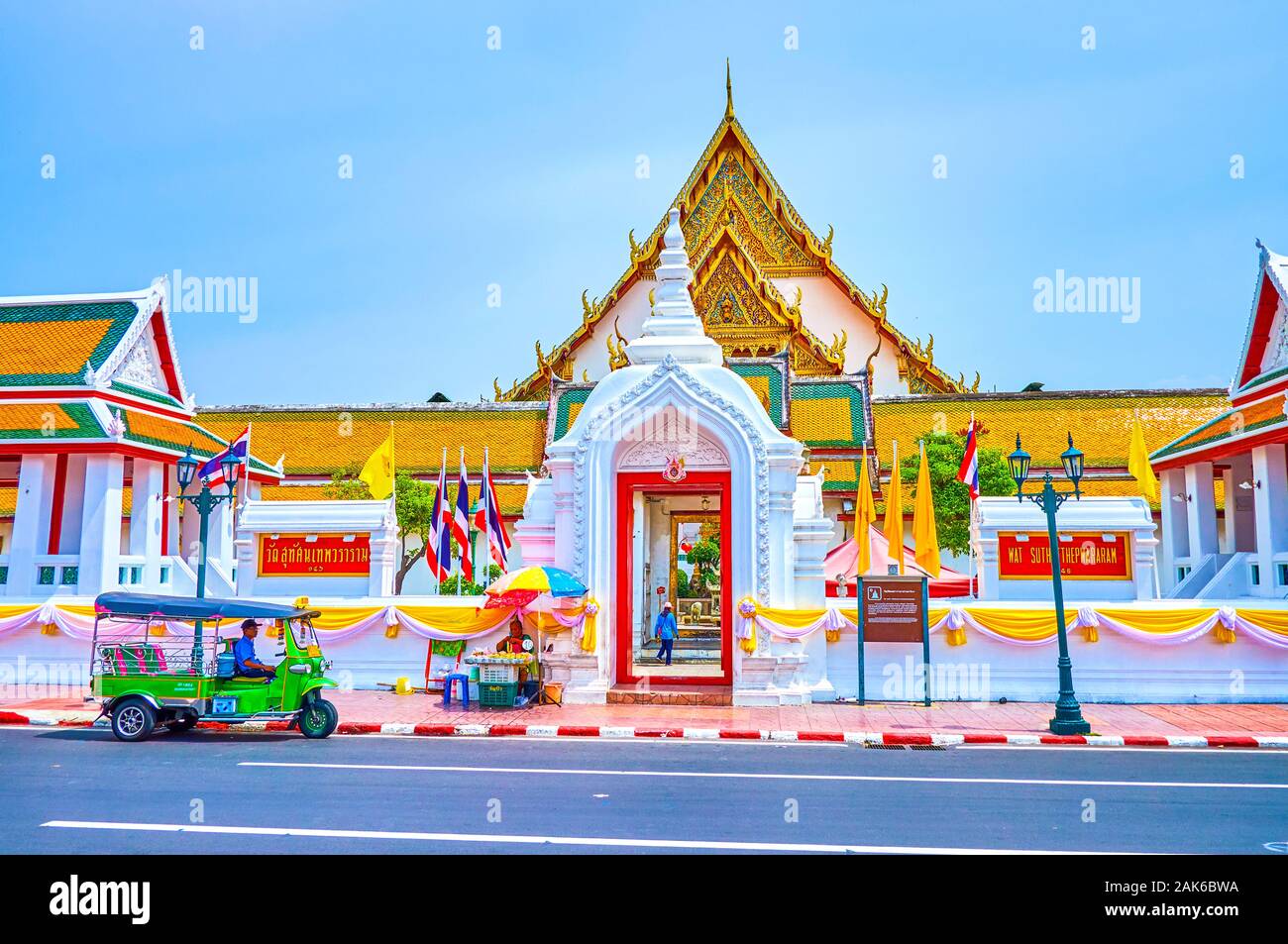 BANGKOK, THAILAND - APRIL 15, 2019: The tuk-tuk rickshaw stands at the open doors of the Wat Suthat temple with a view on inner courtyard of famous re Stock Photo