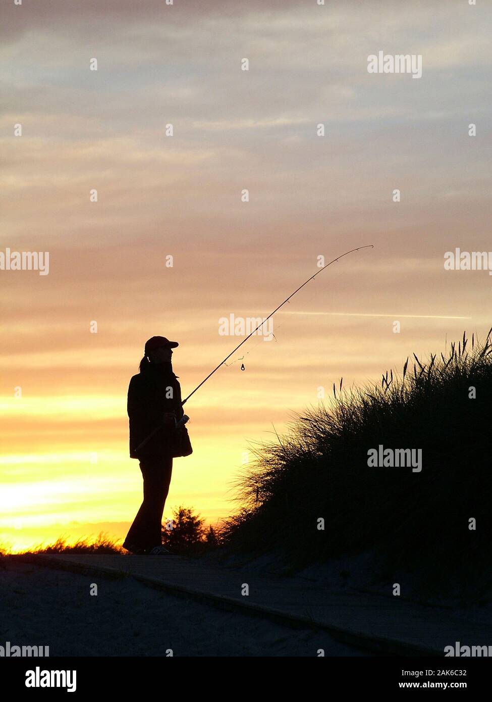 Woman at sunset on the way to the fishing spot Stock Photo