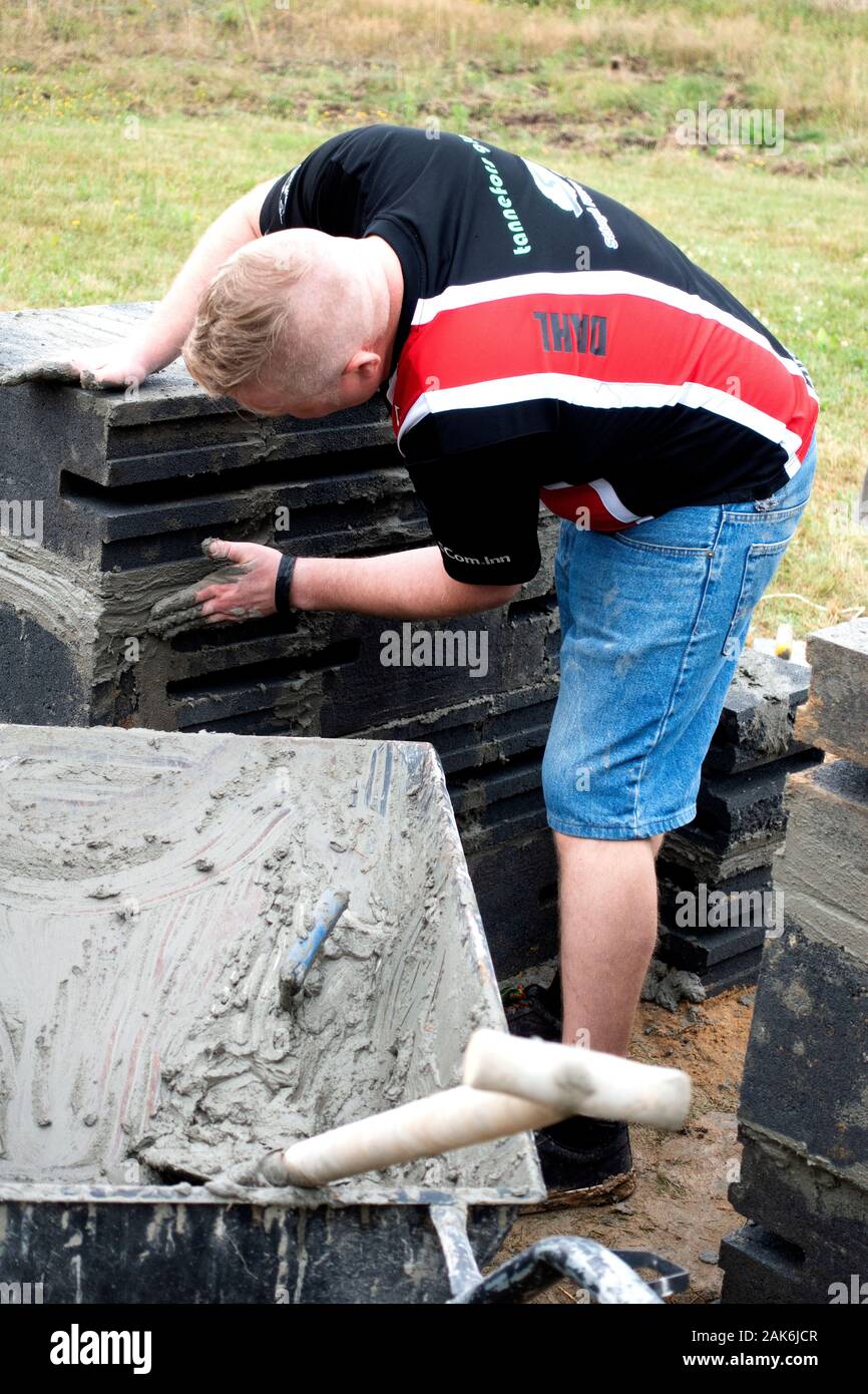 Man adding cement to the bricks for building his outdoor fireplace. Zawady Gmina Rzeczyca Poland Stock Photo