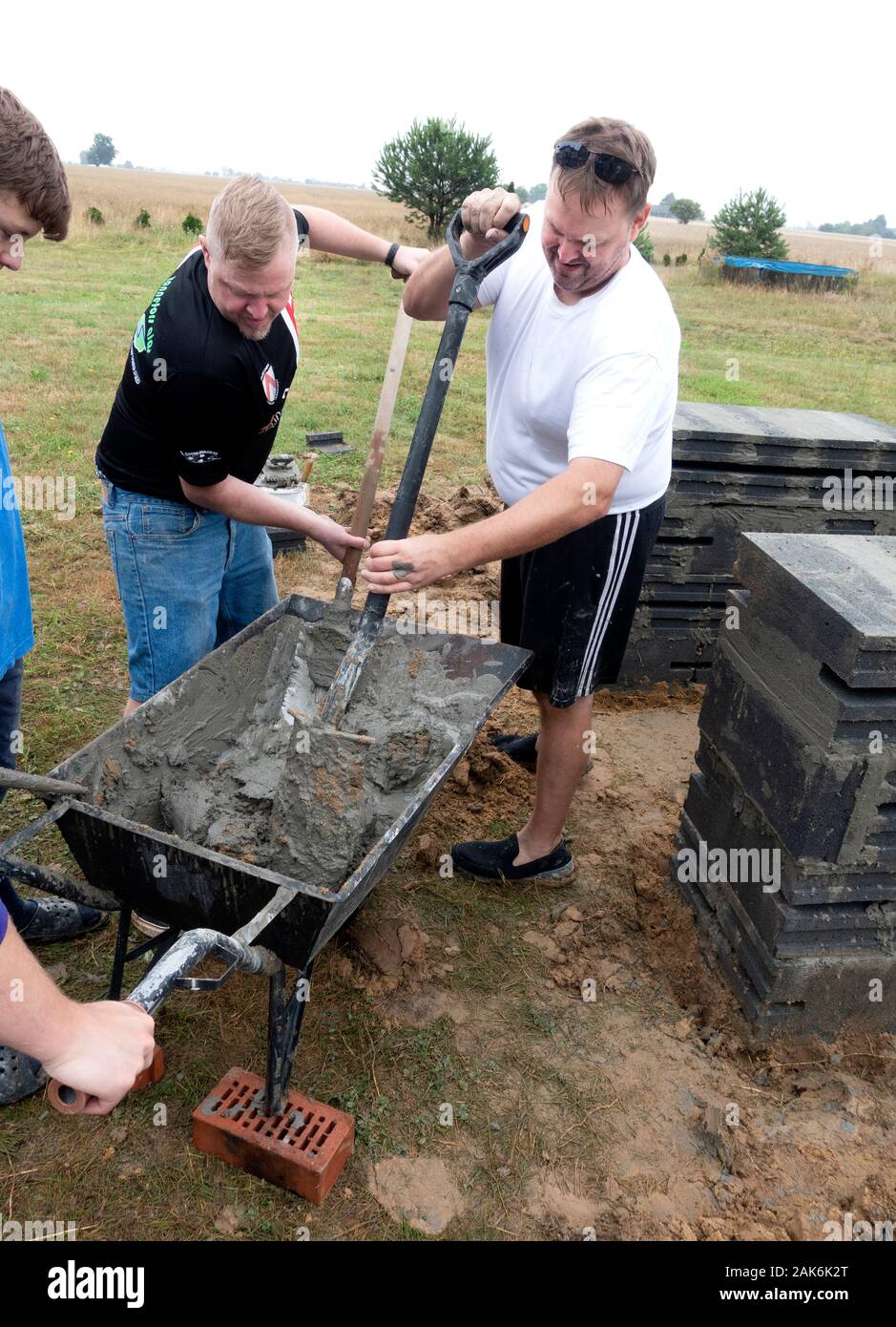 Brothers Mixing Cement In Wheelbarrow Used For Building An Outdoor
