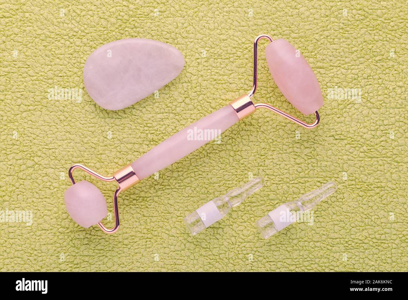 real rose quartz facial roller, massage stone and face serum in ampoules Stock Photo