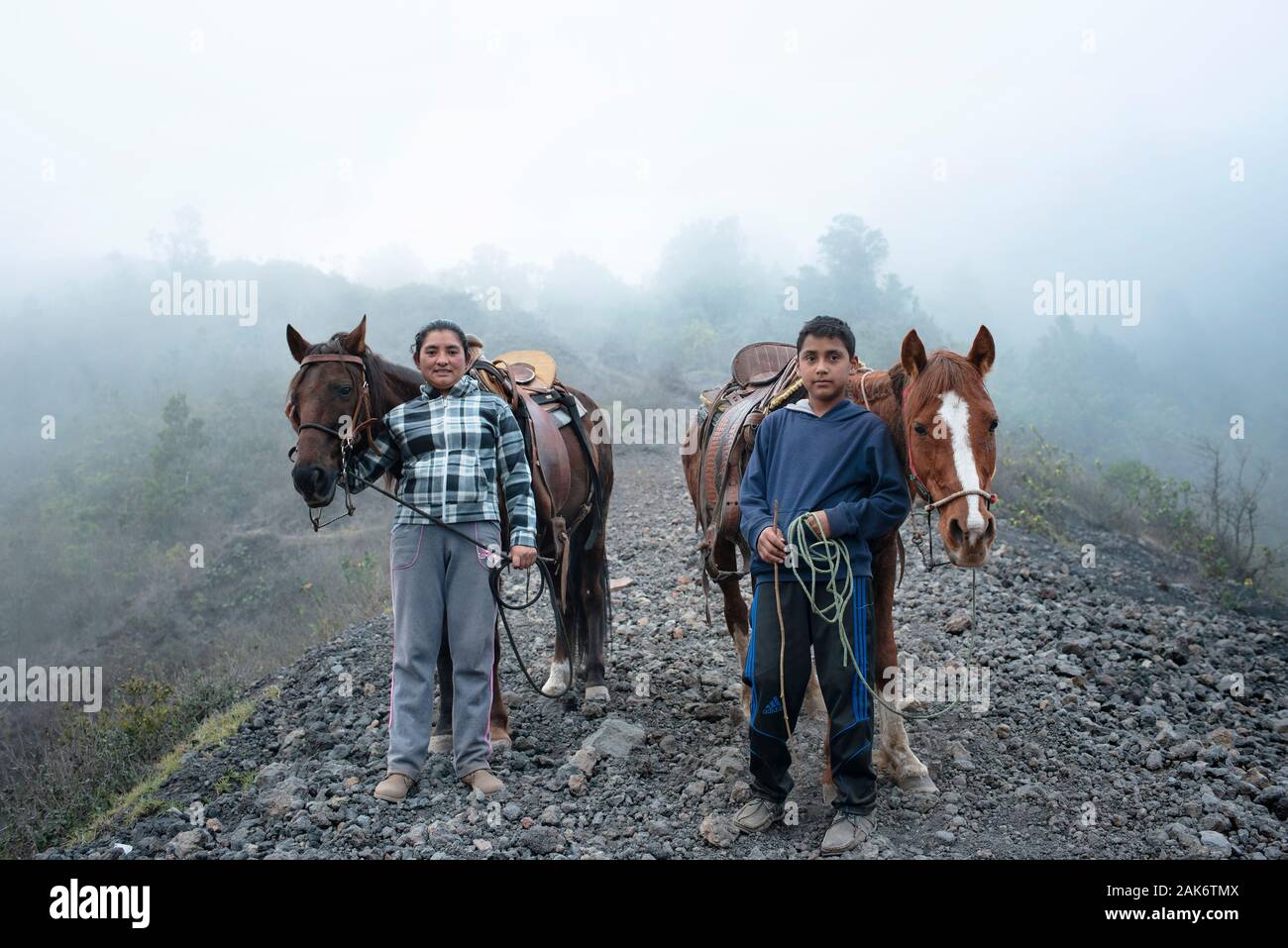 Environmental portrait of a boy and mother. Local family offering horse riding for tourists on the volcanic terrain around Pacaya volcano, Guatemala Stock Photo