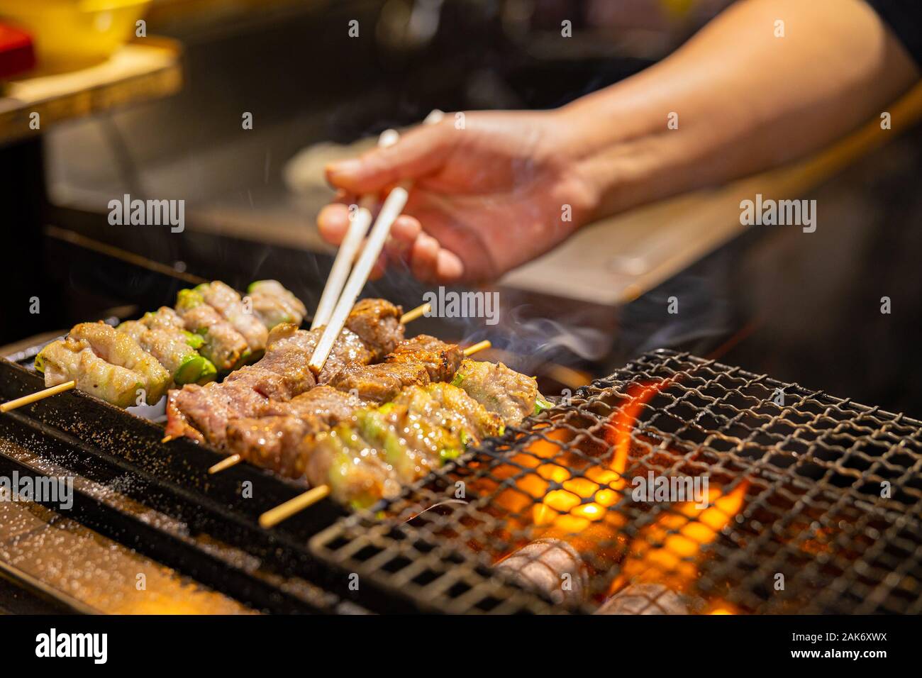 Vendor preparing meat on barbecue grill in Japan Stock Photo
