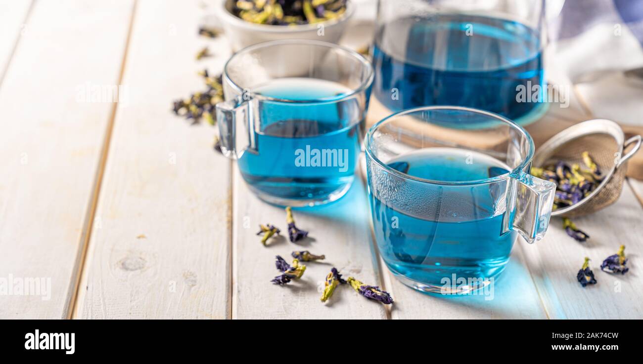 Blue tea in glass cups and glass teapod, white wood background Stock Photo