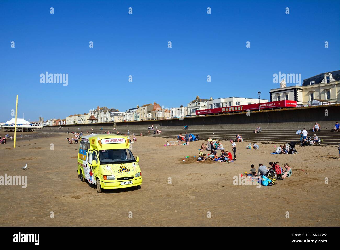 Tourists relaxing on the beach with an ice cream van in the foreground, Burnham-on-Sea, England, UK. Stock Photo