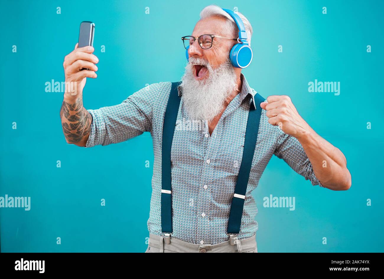 Senior hipster man using smartphone app for creating playlist with rock music - Trendy tattoo guy having fun with mobile phone technology - Tech and j Stock Photo
