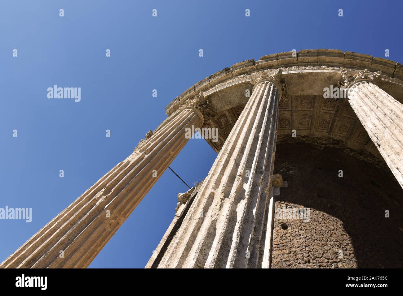 Ruins with columns of the ancient temple of the goddess Vesta in Tivoli. Circular Temple of Vesta on the banks of the river Aniene. Example of Greek R Stock Photo