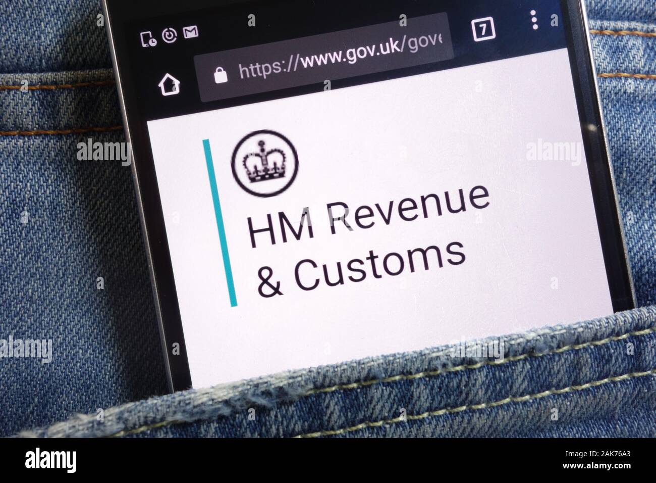 The UK government website for HM Revenue and Customs displayed on smartphone hidden in jeans pocket Stock Photo