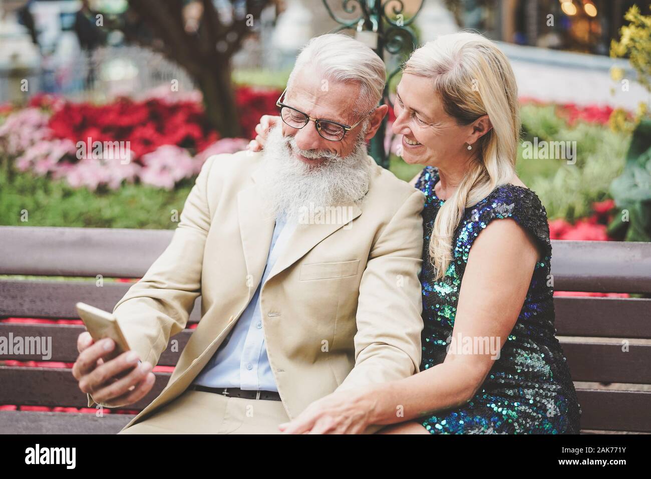 Happy senior couple watching on mobile smartphone outdoor - Mature fashion pensioners having fun with new technology cellphones apps Stock Photo
