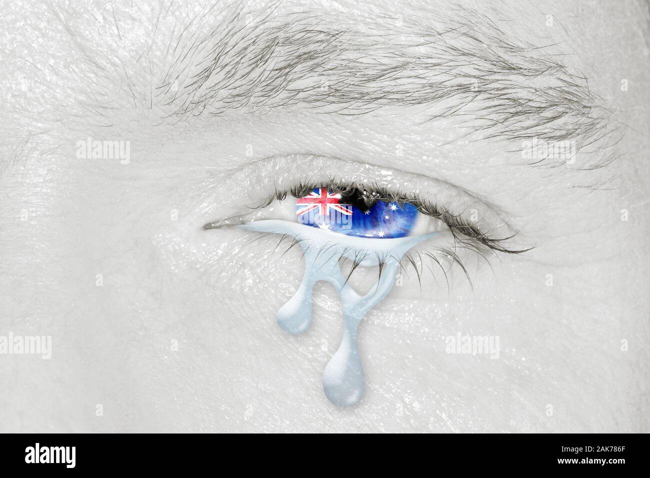 Crying eye with Australian Flag iris on black and white face. Concept of sadness and empathy for bushfire and natural disasters in Australia Stock Photo