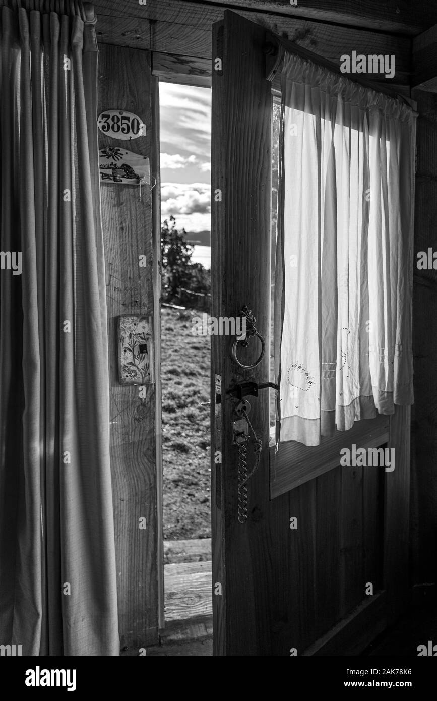 BARILOCHE, ARGENTINA, JUNE 18, 2019: An open door seen from the interior of a wooden cozy and relaxing cabin that leads to the forest and lake, in Stock Photo